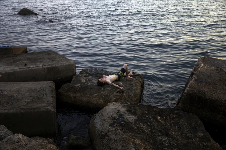Andre forsøger at finde hvile i vandkanten ved Barcelonas kyst. Emilio Morenatti/AP