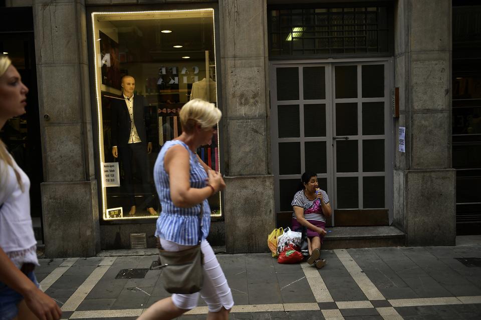 En kvinde har sat sig med en is i en af Pamplonas steghede gader. Alvaro Barrientos/AP