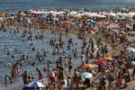 Der er nærmest tale om en folkevandring mod stranden og det vand, der kan levere en smule nedkøling. Manu Fernandez/AP