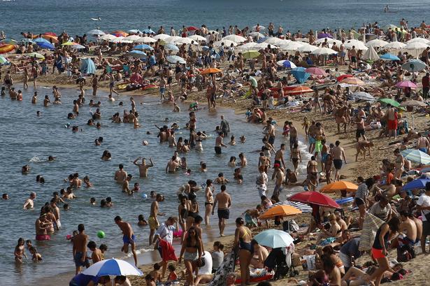 Der er nærmest tale om en folkevandring mod stranden og det vand, der kan levere en smule nedkøling. Manu Fernandez/AP