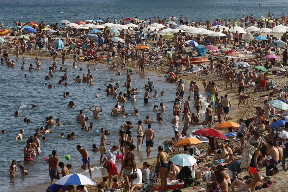 Der er nærmest tale om en folkevandring mod stranden og det vand, der kan levere en smule nedkøling. Manu Fernandez/AP