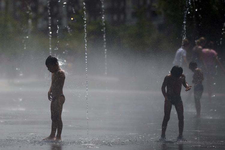 Børn og voksne køler sig i en park i Madrid. Ekstrem varme har lagt sig over Sydeuropa, og det har kostet tre mennesker livet i Spanien. Francisco Seco/AP