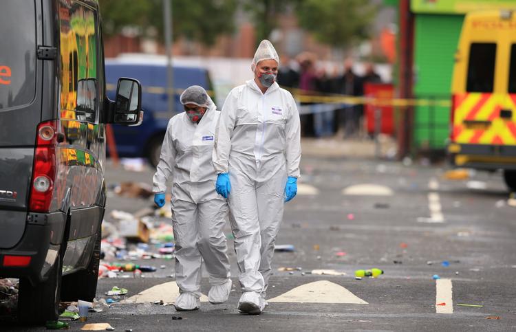 Retsmedicinere undersøger gerningsstedet i bydelen Moss Side i Manchester. Ti blev såret af skud.
    
   Peter Byrne/AP