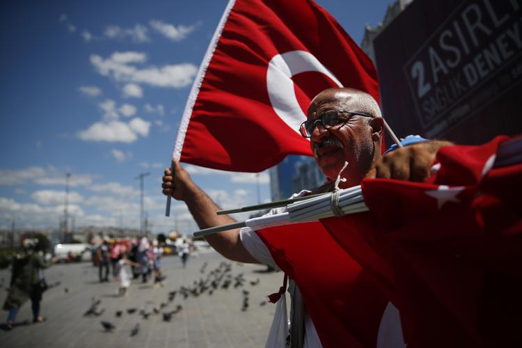 En gadesælger tilbyder tyrkiske flag til forbipasserende på gaden i storbyen Istanbul mandag, mens den tyrkiske centralbank forsøgte at bremse et markant fald i liraens kurs, som truer med at bringe hele Tyrkiets økonomi i knæ. (AP Photo/Lefteris Pitarakis)
   Lefteris Pitarakis/AP