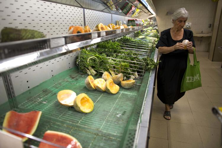 Krisen i Venezuela er høj. Billedet er taget i foråret, hvor en kvinde tjekker prisen på en melon.  Ariana Cubillos/AP