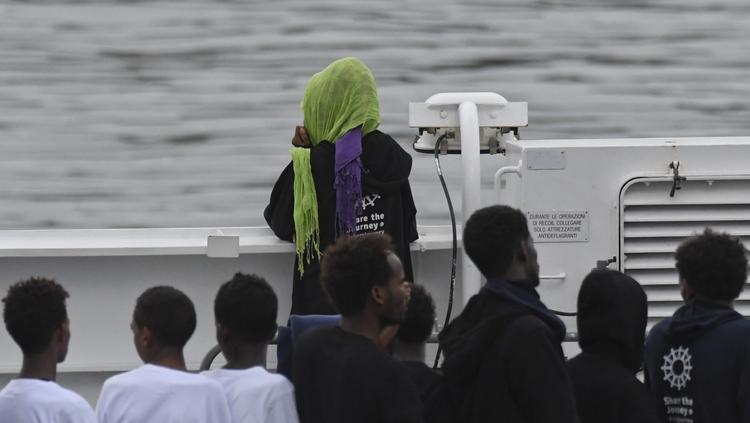 Migranter kigger ind mod land ombord på redningsbåden Diciotti i hanen i Catania på Sicilien, hvor skibet har ligget siden i mandags. Salvatore Cavalli/AP