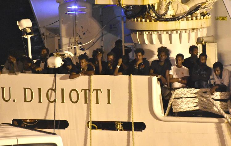 Migranter gør klar til at gå fra borde efter flere dages venten i Catanias havn. De er blev et billede på EU's handlingslammelse og får nu en repræsentant for den italienske regering til at true med at nedlægge veto mod unionens budget. Orietta Scardino/AP