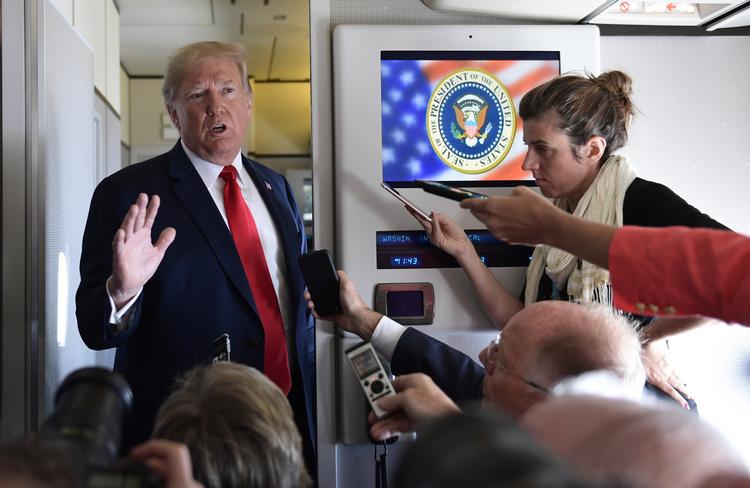 Prøsodent Domald Trump taler med journalister på en flyvetur mellem Billings og Fargo fredag, mens stormvejr om anonym kronik i avisen The New York Times raser. Susan Walsh/AP