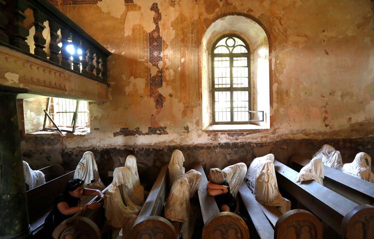 En gruppe franske turister er på besøg i den lokale kirke i Lukova, hvor Jakub Hadravas kunstværk 'My Mind' - en gruppe spøgelseslignende figurer - efterhånden er blevet en turistattraktion. Petr David Josek/AP/AP