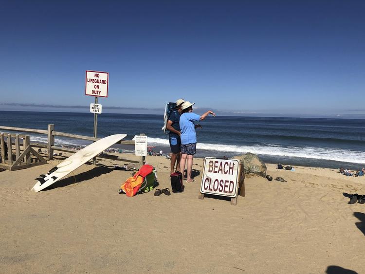 To personer kigger ud på vandet ved Newcomb Hollow Beach i Wellfleet, Massachusetts. En mand blev lørdag bidt af en haj og døde senere af sine kvæstelser. Det er første gang i 80 år, at en person dør som følge af et hajangreb i staten.
   Susan Haigh/AP