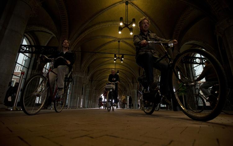 Cyklister kører på en cykelsti under Rijksmuseum i Amsterdam. Har de mobilen i hånden, kan det koste en bøde. Ny lov skal dæmme op for ulykker som følge af, at cyklister ser mere på deres mobil end på cykelstien.  Peter Dejong/AP