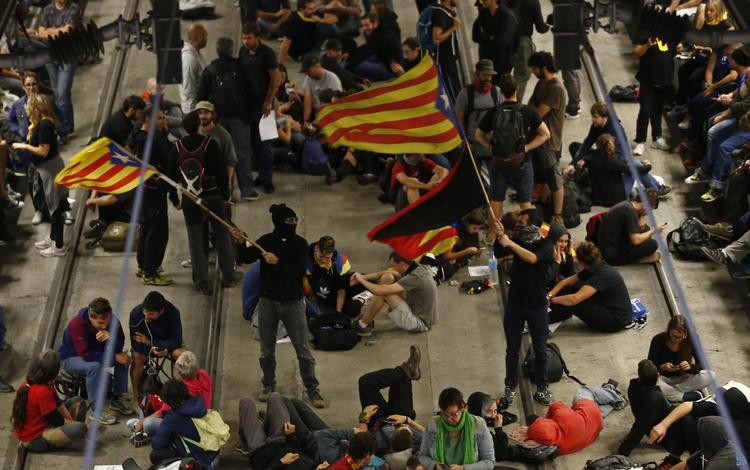 Aktivister svinger det catalanske flag og blokerer jernbanespor i byen Girona for at markere årsdagen for den underkendte uafhængighedsafstemning, der i 2017 endte med massive sammenstød mellem vælgere og politi.
   Manu Fernandez/AP