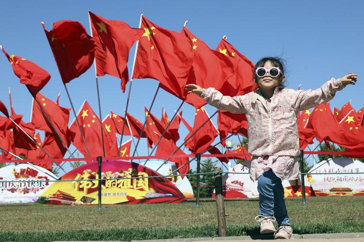 En dreng løber forbi kinesiske flag, da Kina i mandags fejrede sin nationaldag. Drengen vil vokse op i et land, hvor ni ud af ti ser lyst på fremtiden ifølge en ny undersøgelse.
 Ng Han Guan/AP
