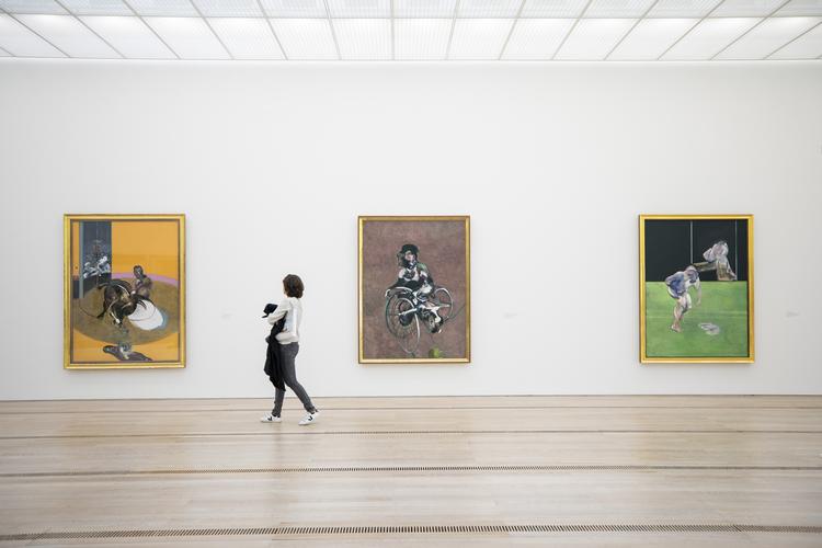En museumsgæst foran tre malerier af den britiske maler Francis Bacon udstillet i Schweiz.  Patrick Straub/AP