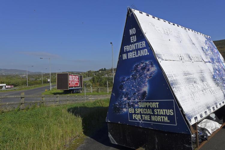 Den irske grænse er normalt nærmest usynlig, men i den seneste tid er den blevet beklædt med politiske budskaber om Brexits konsekvenser.
    In this photo taken on Wednesday, Oct. 10, 2018, a sign in a parking lot of a cemetery reads: "No EU border in Ireland" near Carrickcarnan, Ireland, just next to the Jonesborough Parish church in Northern Ireland. The land around the small town of Carrickcarnan, Ireland is the kind of place where Britain’s plan to leave the European Union walks right into a wall - an invisible one that is proving insanely difficult to overcome. Somehow, a border of sorts will have to be drawn between Northern Ireland, which is part of the United Kingdom, and EU member country Ireland to allow customs control over goods, produce and livestock once the U.K. has left the bloc. (AP Photo/Lorne Cook)
   Lorne Cook/AP