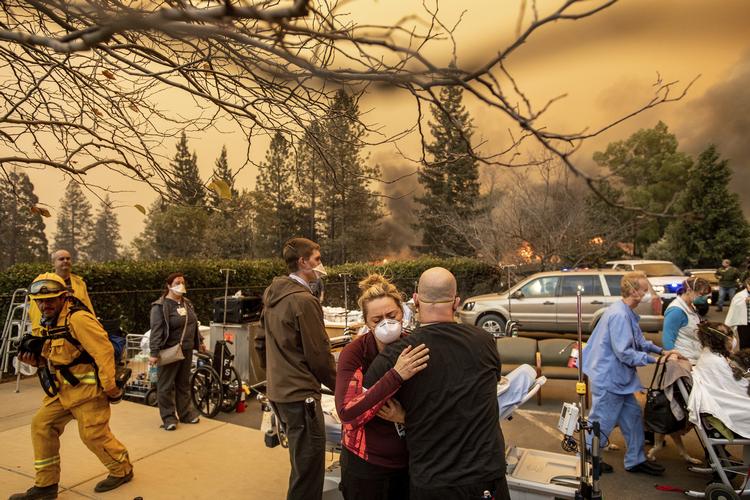 Sygeplejeste Cassie Lerossignol krammer med en kollega mens Feather River Hospitalet brænder. Noah Berger/AP