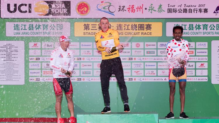 Ilya Davidenok er i sin nyerhvervede gule førertrøje i fuld gang med champagnefesten ved hyldestseancen efter 3. etape i Tour of Fuzhou sammen med nr. 1 i ungdomskonkurrencen Xianjing Lyu (t.v.) og bjergkongen Hanibal Tesfay. 