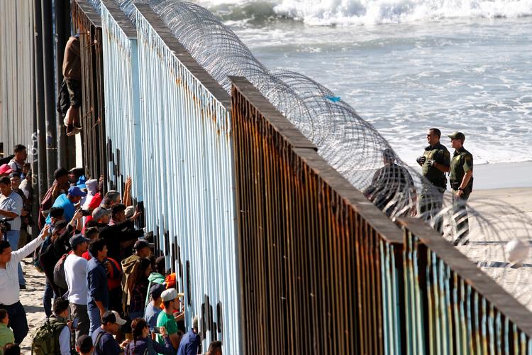 De første af migranter fra de seneste ugers meget omtalte karavane er fremme ved grænsen til USA, nærmere bestemt ved det vestligste punkt, den mexicanske grænseby Tijuana. På den amerikanske side af hegnet ruller soldater pigtråd ud. Jorge Duenes/Ritzau Scanpix
