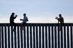To honduranske mænd poserer for en fotograf på grænsemuren til USA i grænsebyenTijuana i  Mexico, inden de kravler ned igen på den mexicanske side. Foto: Gregory Bull/AP