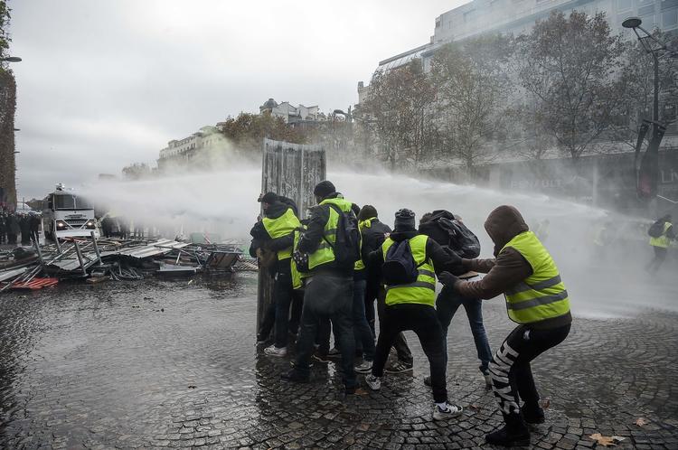 Demonstranter forsøger at modstå en vandkanon ved Champs Elysees i Paris lørdag den 24 november. Foto: Lucas Barioulet/Ritzau Scanpix