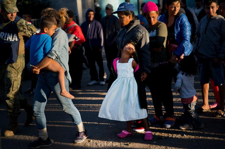 En lille pige venter på mad ved en migrantlejr i mexicanske Tijuana. Flere børn end tidligere kommer med på folks rejser, når der skal søges om ophold eller asyl i USA. Tijuana har erklæret undtagelsestilstand. Foto: Ramon Espinosa/AP