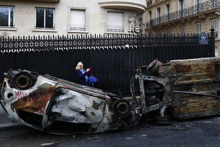 En kvinde fotograferer noget af resultatet af gårsdagens uro i Paris.  Foto: Thibault Camus/AP