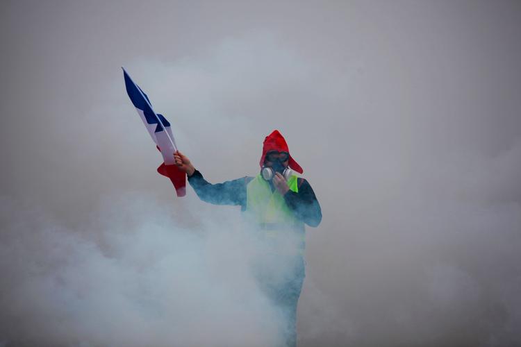 En demonstrant fra De Gule Veste holder det franske flag under weekendens uro i Paris. De Gule Veste siger, at kampen ikke er slut.
 Foto: -/Ritzau Scanpix