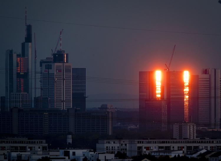 Solnedgangen spejler sig Deutsche Banks tårne i Frankfurt.  Foto: Michael Probst/AP