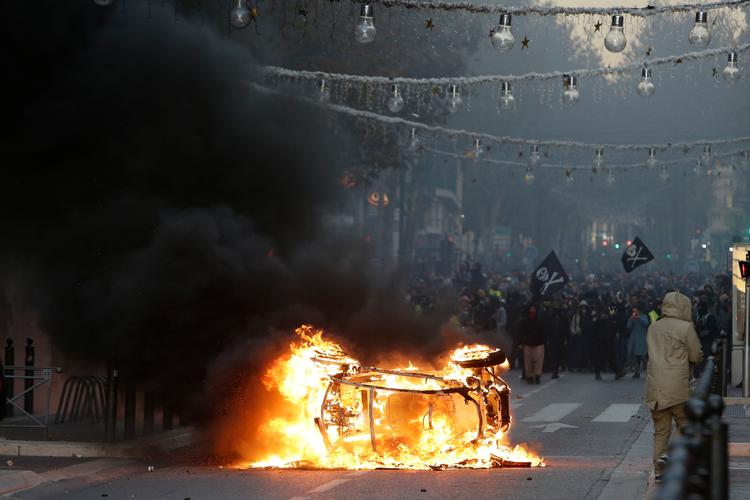 Demonstranter har sat ild til en bil under demonstrationer i lørdags i Frankrigs næststørste by Marseille. 
     Foto: Claude Paris/AP