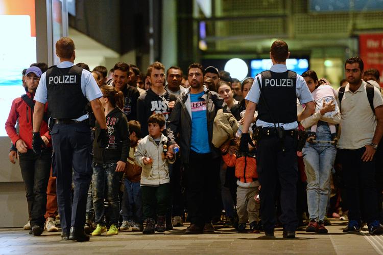 FLygtninge og migranter ankommer til Münchens banegård i 2015, mens politiet ser til. Nye tal viser, at mange asylansøgere, der kom til Tyskland det år, er kommet i arbejde eller er under uddannelse.   Foto: Andreas Gebert/AP