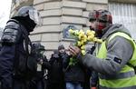 En demonstrant med den karakteristiske gule vest, holder en buket roser foran en politibetjent under en demonstration lørdag 15. december i Paris. Omfanget af weekendens demonstrationen vil give et fingerpeg om, hvorvidt den franske regering er ved at ride stormen af ift. befolkningens utilfredshed.  Foto: Kamil Zihnioglu/AP
