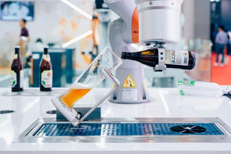 En robotarm fra den tyske producent Kuka hælder øl op ved en robotmesse i Wuhan i Kina. Prost. Eller chin-chin. Den kinesiske producent af hvidevarer Midea købte i 2016 aktiemajoriteten i Kuka.

   Foto: Ma luyao/Ma luyao - Imaginechina