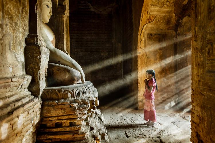 Det er bedetid i et af de små templer i Bagan, Myanmar, hvor en lille pige tager et kort stop på vej til skole.  Foto: Stefano Pensotti/Travel Photographer of the Year
