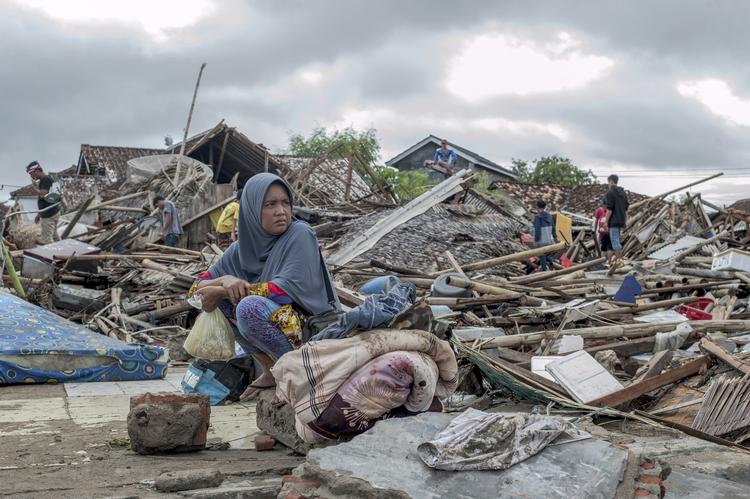 En overlever sidder ved sit hus efter tsunamien Foto: Fauzy Chaniago/AP