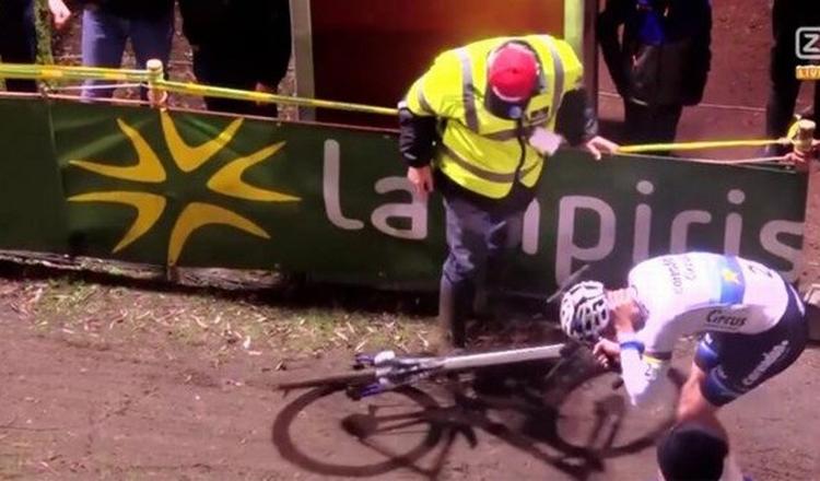 Mathieu van der Poel tager sig til nakken og retter på cyklen, mens stewarden i gul vest, som han er kollideret med, betuttet ser til. 