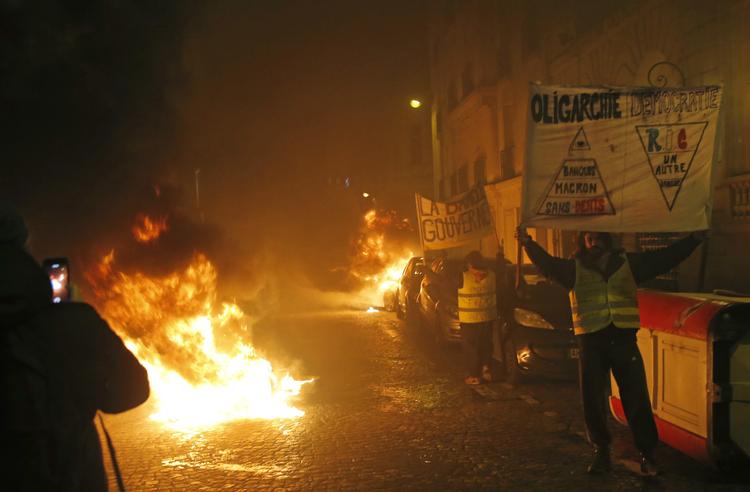 Demonstranter holder bannere og laver bål i gaden nær Champs Elysees lørdag den 5. januar i Paris. Hundredevis af demonstranter forsøgte lørdag dag og nat at puste nyt liv i De Gule Veste. Foto: Michel Euler/AP