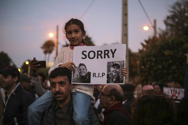 En pige i Rabat, Marokko, bærer billedet af norske Maren Ueland og danske Louisa Vesterager Jespersen under en mindehøjtidelighed uden for den danske abassade.  Foto: Mosa'ab Elshamy/AP