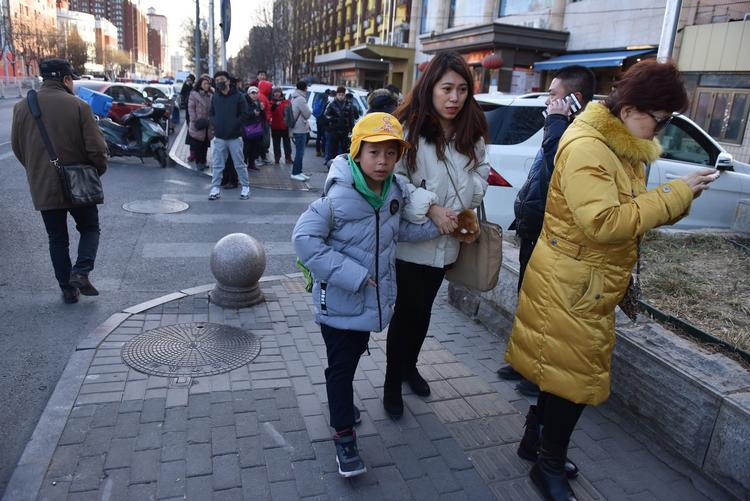 Et barn eskorteres væk fra en skole i Beijing efter angrebet tirsdag, hvor 20 børn blev såret. De blev angrebet af en mand med kniv. Foto: Greg Baker/Ritzau Scanpix