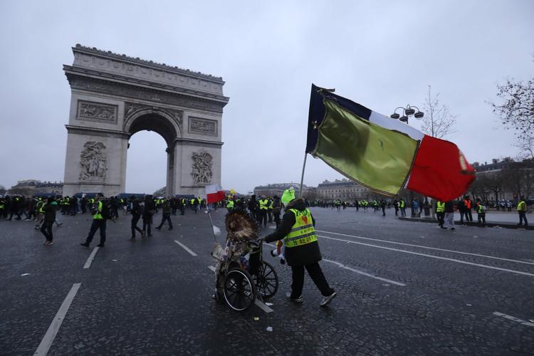 Demonstranter fra bevægelsen De Gule Veste nærmer sig Triumfbuen i Paris, hvor fransk politi senere lørdag måtte benytte tåregas og vandkanoner for at holde styr på de demonstrerende.    Foto: Ludovic Marin/Ritzau Scanpix