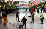 En strandet passager går forbi strejkende lufthavnsansatte i Tysklands største lufthavn i Frankfurt i nat.  Foto: Kai Pfaffenbach/Ritzau Scanpix