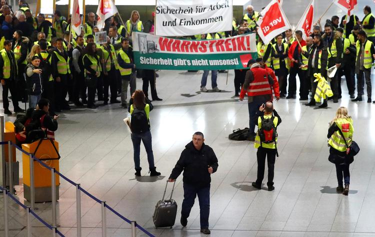 En strandet passager går forbi strejkende lufthavnsansatte i Tysklands største lufthavn i Frankfurt i nat.  Foto: Kai Pfaffenbach/Ritzau Scanpix