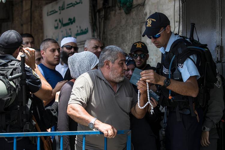 En israelsk betjent tjekker en palæstinensers id-kort ved en vejspærring uden for den gamle by i Jerusalem.  Foto: Tsafrir Abayov/Ritzau Scanpix