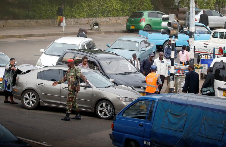 Soldater og politibetjente dirigerer bilister, som holder i kø efter benzin i Zimbabwes hovedstad, Harare.  Foto: Philimon Bulawayo/Ritzau Scanpix