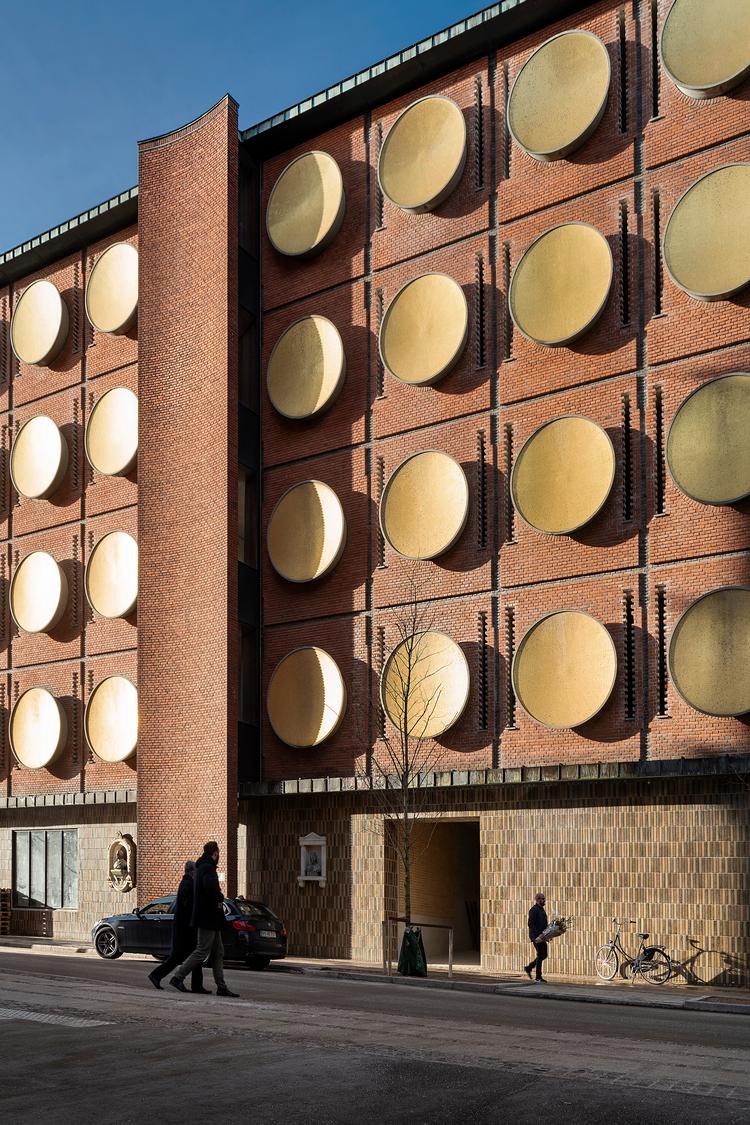 Facaden af lageret med de karakterfulde konkave former er bevaret og gjort anvendelig til hotel ved at åbne muren omkring guldskjoldene med 'lynlåse', hvor dagslys kan komme ind.   Foto: Jens Lindhe