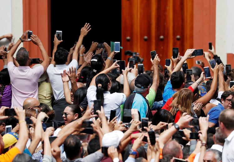 Venezuelanere tager billeder, da Juan Guaidó, der har udråbt sig selv om præsident, ankommer til en pressekonference i Caracas tidligere fredag.  Foto: Carlos Garcia Rawlins/Ritzau Scanpix