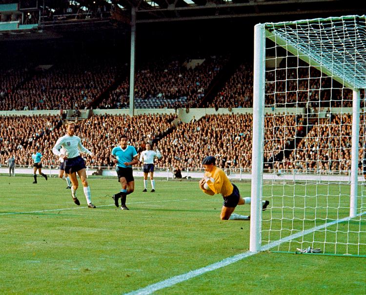 Under en landskamp mellem England og Uruguay ved VM 1966 i England redder Gordon Banks, her iført en klædelig kasket, et skudforsøg, mens holdkammeraten Jackie Charlton ser til.
     Foto: /Ritzau Scanpix