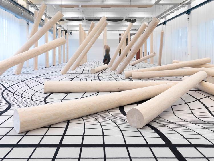 Claudia Comtes enorme installation 'I Have Grown Taller from Standing with Trees' korresponderer mønstret i gulvtæppet med den måde, de afbarkede stammer opfører sig på.  Foto: Copenhagen Contemporary
