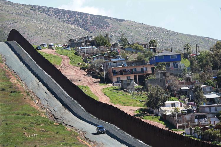 En bil kører langs hegnet mellem Mexico og USA i Otay Mesa, Californien. Den helt store varme kartoffel i USA lige nu er Trumps bebudede nødretstilstand, der skal finansiere mur langs hele grænsen.  Foto: Sandy Huffaker/Ritzau Scanpix