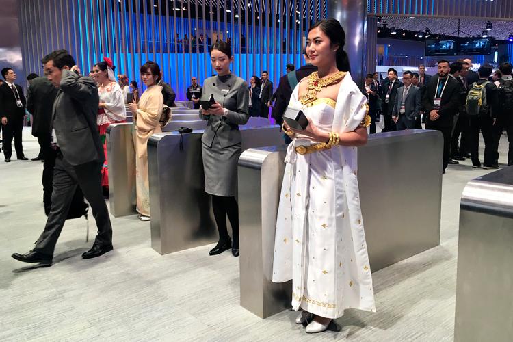 
Værtinder i nationaldragter står ved indgangen til Huaweis enorme stand til mobilmessen MWC i Barcelona. Kvinderne er fastansatte og rejser verden rundt for at promovere det kinesiske selskab.    Foto: Sebastian Stryhn