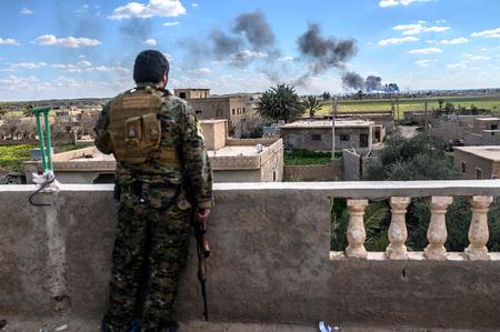 En soldat fra de syriske demokratiske styrker (SDF) betragter Islamisk Stat blive bombarderet med artilleri det østlige Syrien. Ifølge debattør Frida Ingeborg Tingberg Petersen har Danmark et juridisk ansvar for at hjemtage og retsforfølge de danskere, der er rejst til Mellemøsten for at kæmpe under terrorgruppens faner. 
   Foto: Bulent Kilic/Ritzau Scanpix
